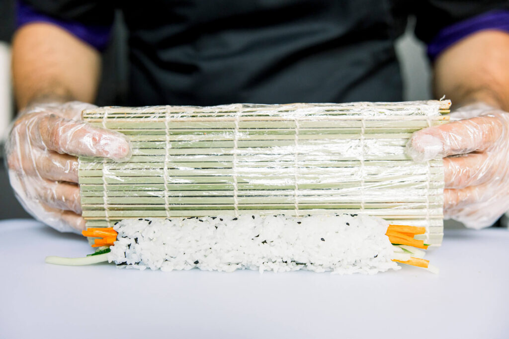 Sushi being rolled by a bamboo mat